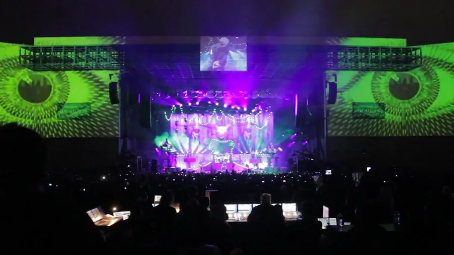 Wide view of the Knotfest stage with giant green eye visuals projected on both venue walls