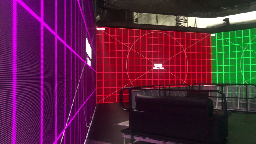 Wide physical LED volume view with magenta, red, and green wall faces and railings