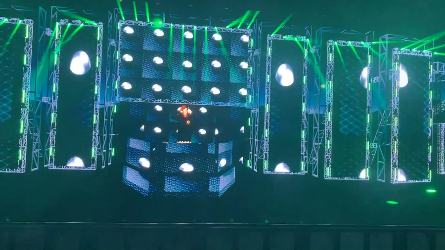 Animated virtual stage with green lighting, circular screen content, and side LED walls