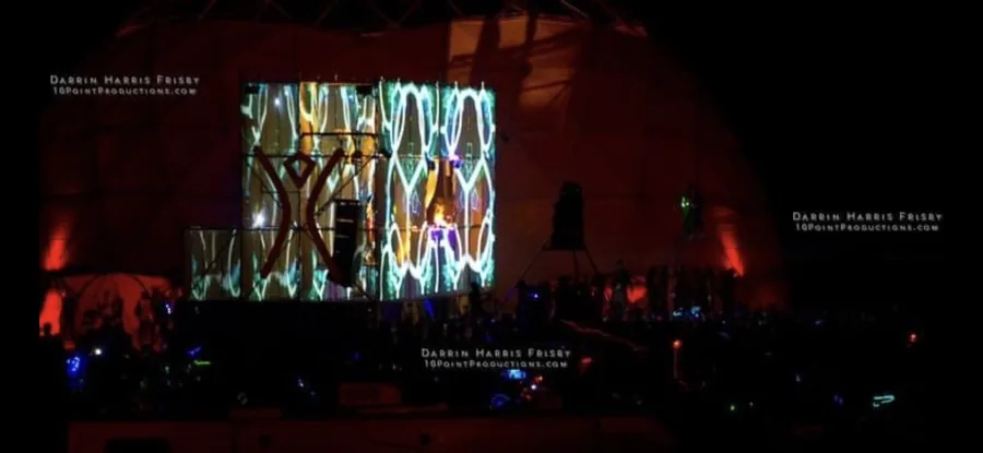 The Tower of Babel projection surface glowing with vertical abstract patterns at night