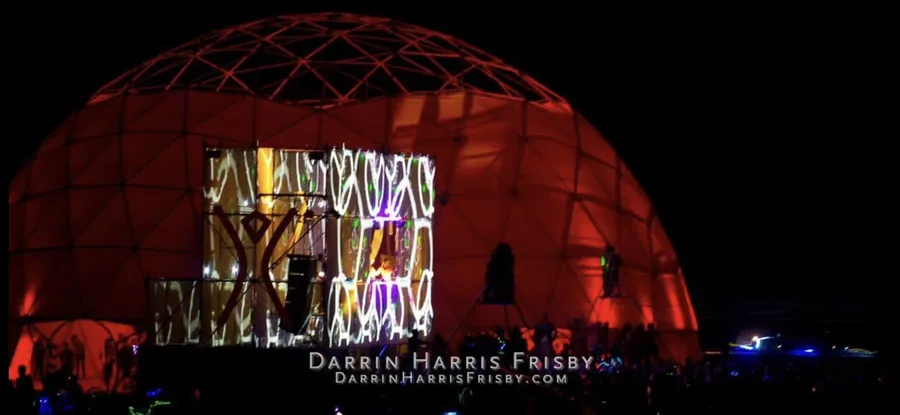 The Tower of Babel mapped stage framed by the Root Society dome at night