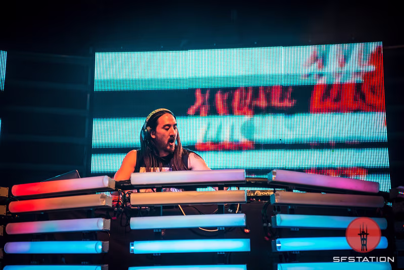 Steve Aoki at the touring video booth with red and cyan content across the LED surfaces