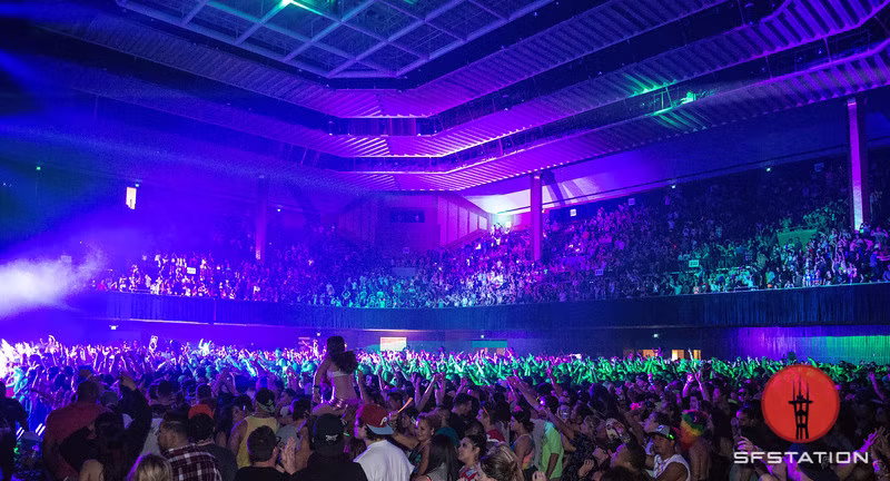 Packed Bill Graham Civic Auditorium crowd washed in cyan and violet show light