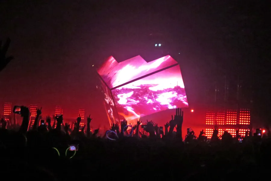 Magenta Cube 2.1 glowing above raised hands in the audience