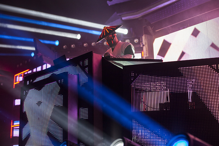 Close performance view of Datsik at the glowing Shogun LED DJ booth beneath blue stage beams