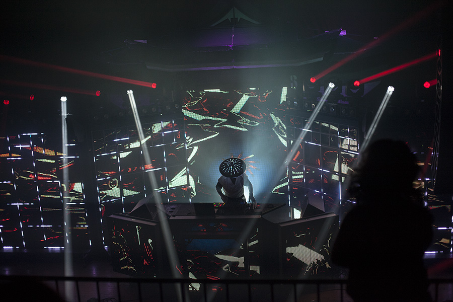 Wide performance view of the Shogun Stage with fragmented red and white LED content and overhead beams