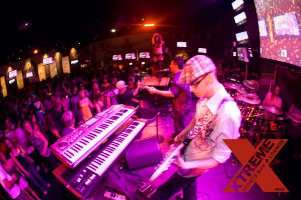 DJ and keyboard performer working above the XTREME dance floor with screens filling the back wall
